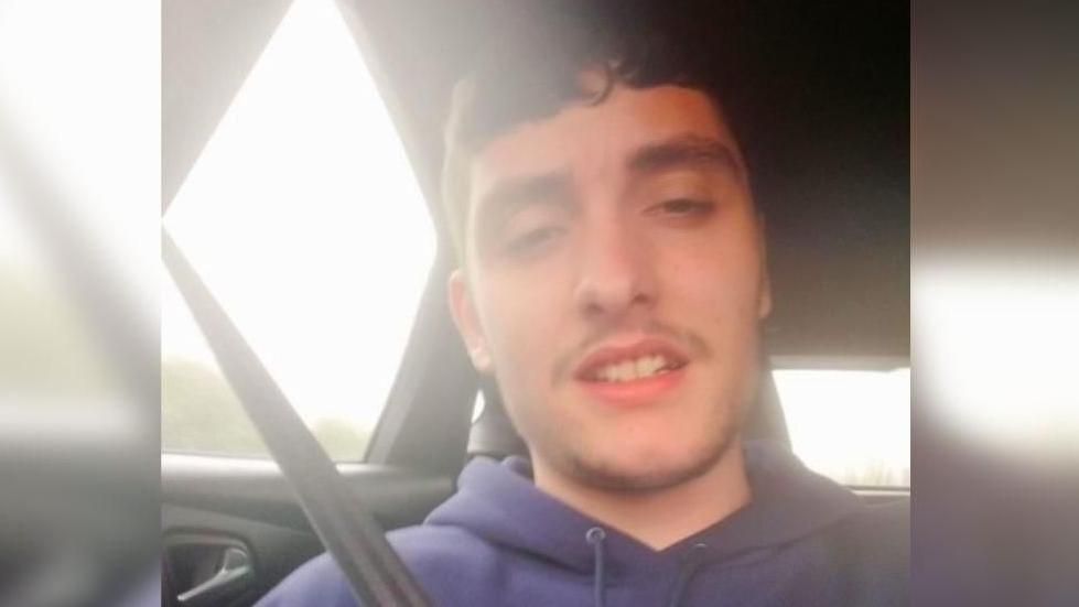 A selfie of Jack Edwards sitting in a car with a seatbelt on and wearing a dark blue hoody.