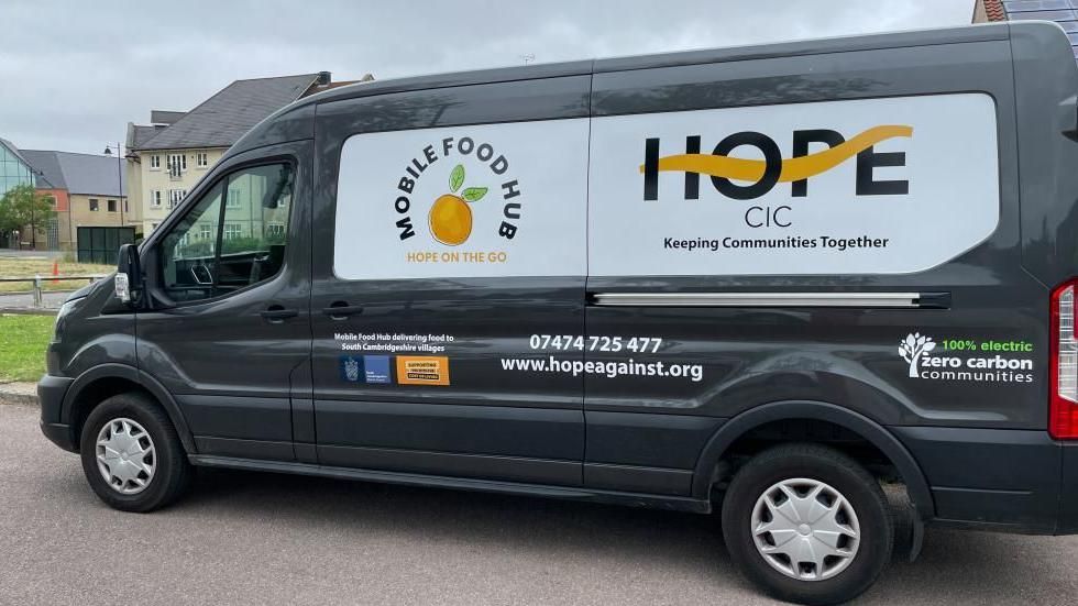 A side view of a black van with signage saying Hope and Mobile Food Hub 