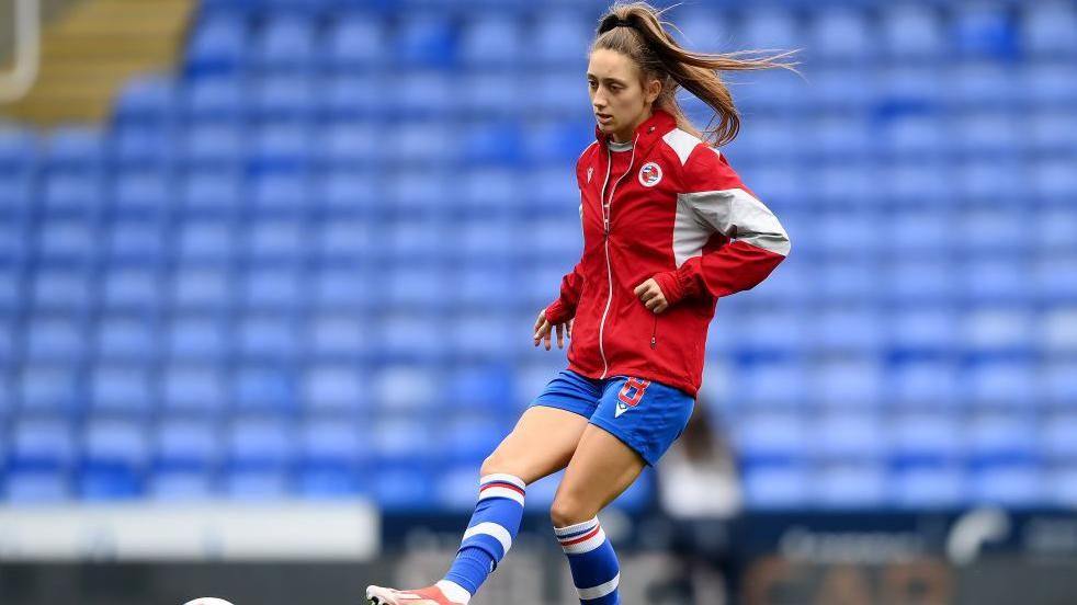 Tia Primmer warming up by kicking a ball before a Reading game 