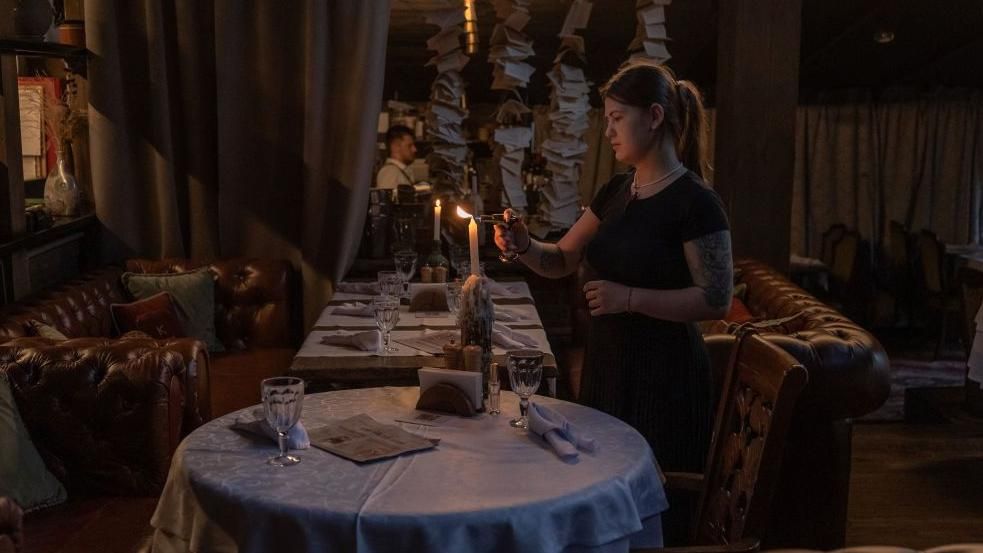 A woman lights a candle during a blackout in Kyiv