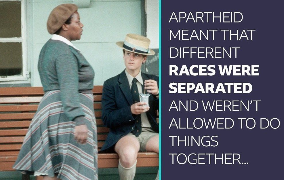 A black woman passes a young white man on a bench in South Africa. A Newsround caption reads: Apartheid meant that different races were separated and weren't allowed to do things together.