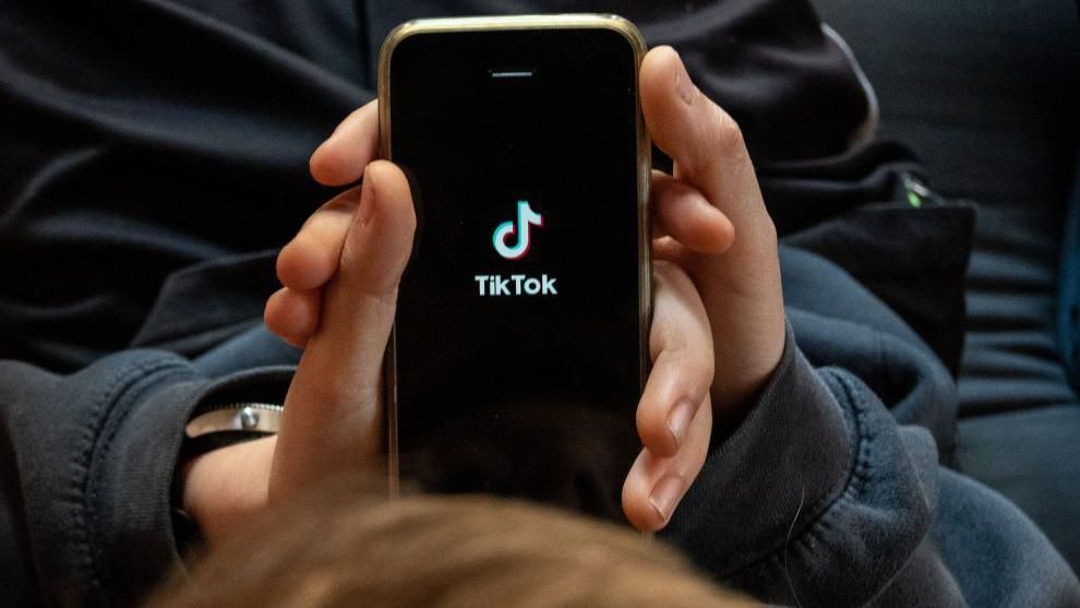 A boy looks at the TikTok app on a smartphone