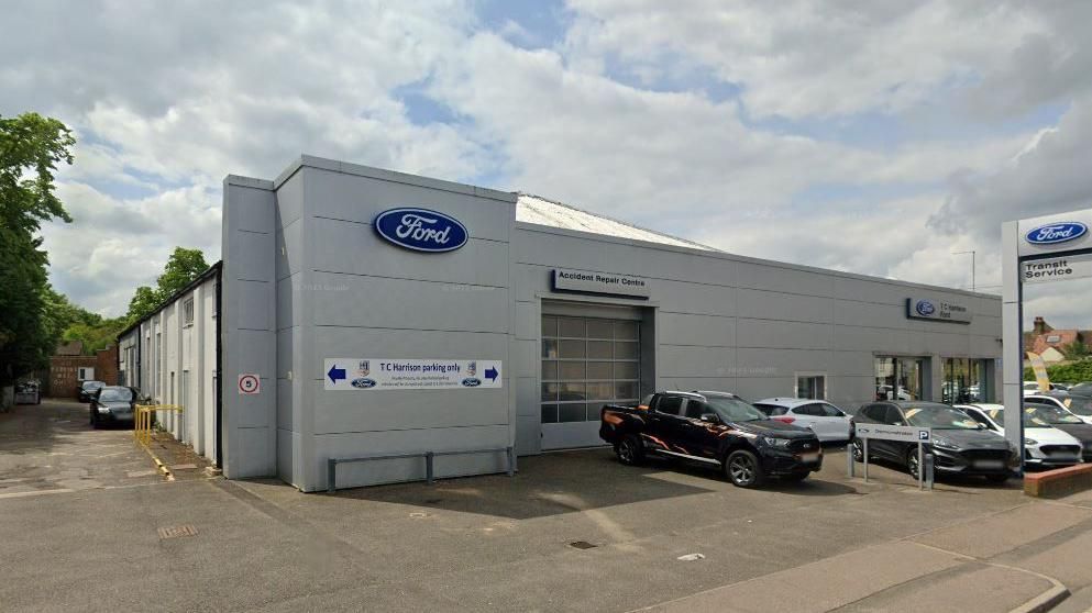 The TC Harrison Ford garage in St Neots - a grey coloured showroom and repair centre with vehicles parked on the forecourt