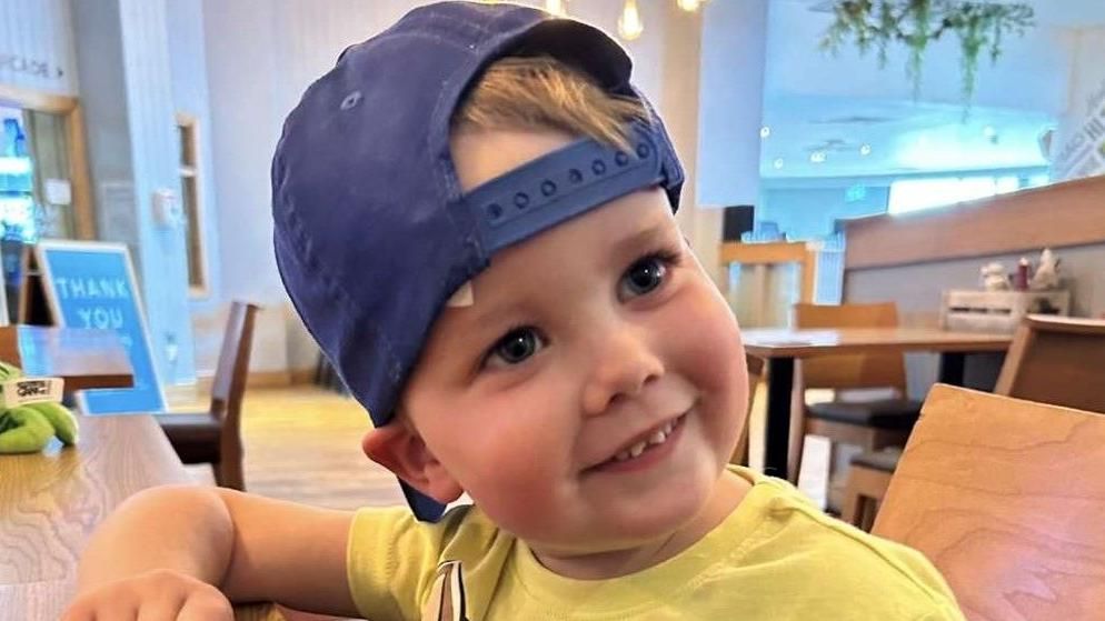 A little boy in a blue cap smiling at the camera