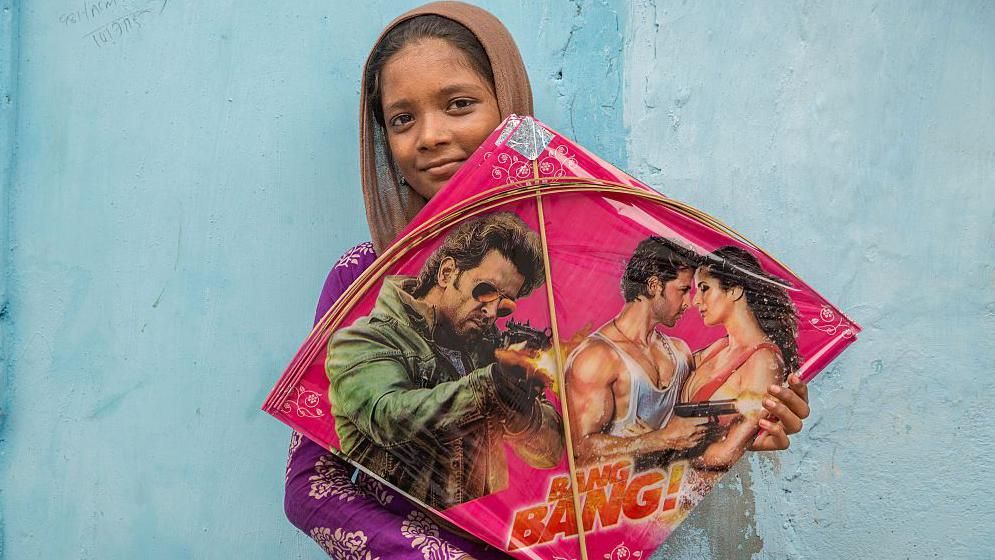 Kite maker Sheikh Kayamat, age 14, shows her kite that she is making. A home based worker who has been trained by SEWA, using special tables and chairs, the average pay is 100 rupees a day for 1,000 kites. 