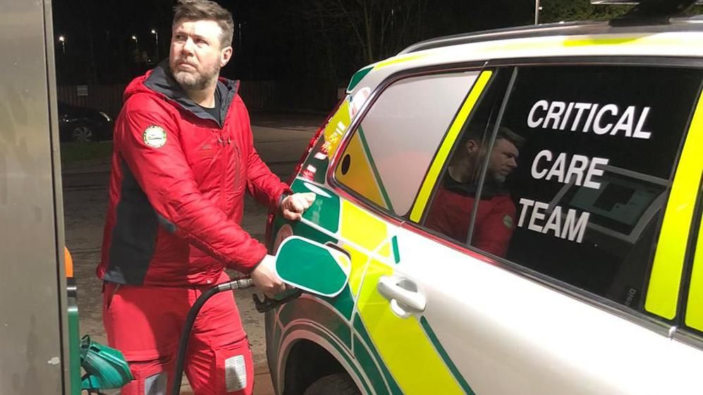 A paramedic filling a car with petrol 