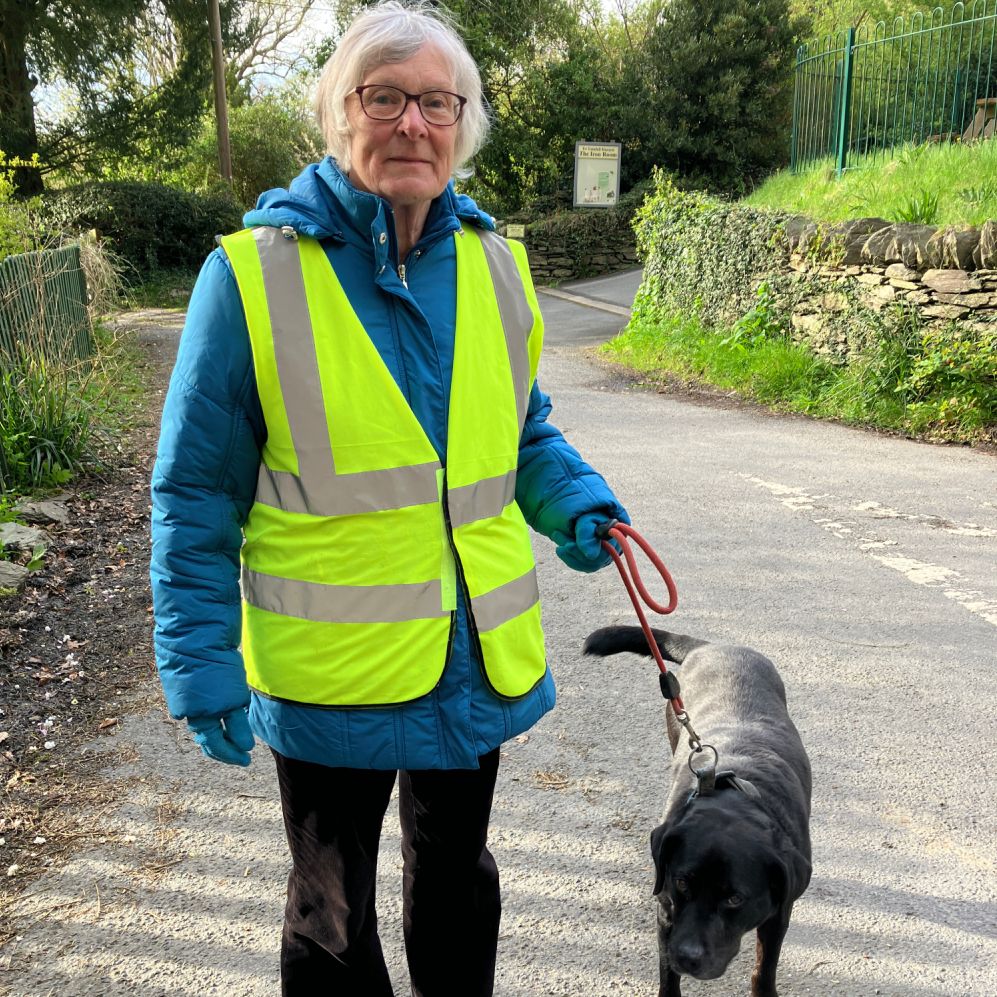 Celia Davies in high-vis jacket with Rosie the dog by the side of the road