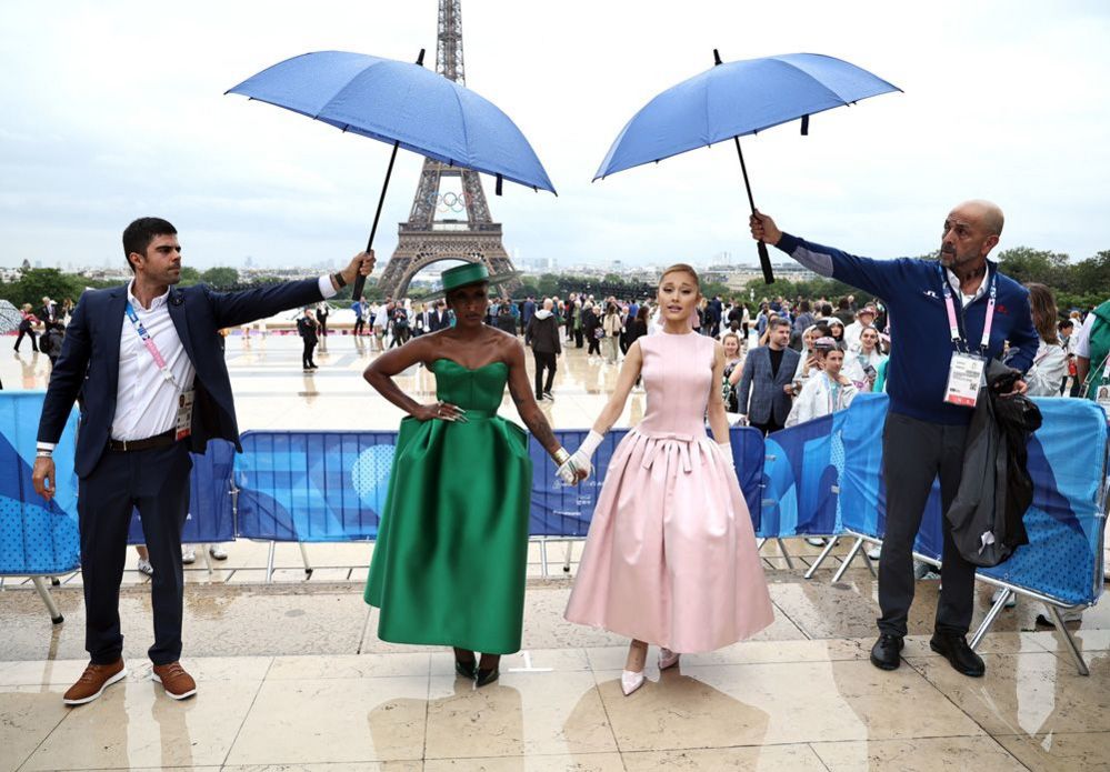 Under umbrellas Ariana Grande hold hands with Cynthia Erivo as they arrive at the Trocadero