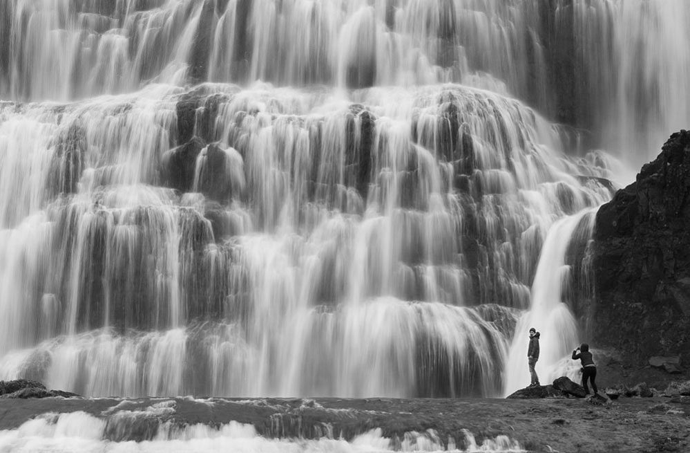 Две фигуры у водопада Диньянди в Исландии