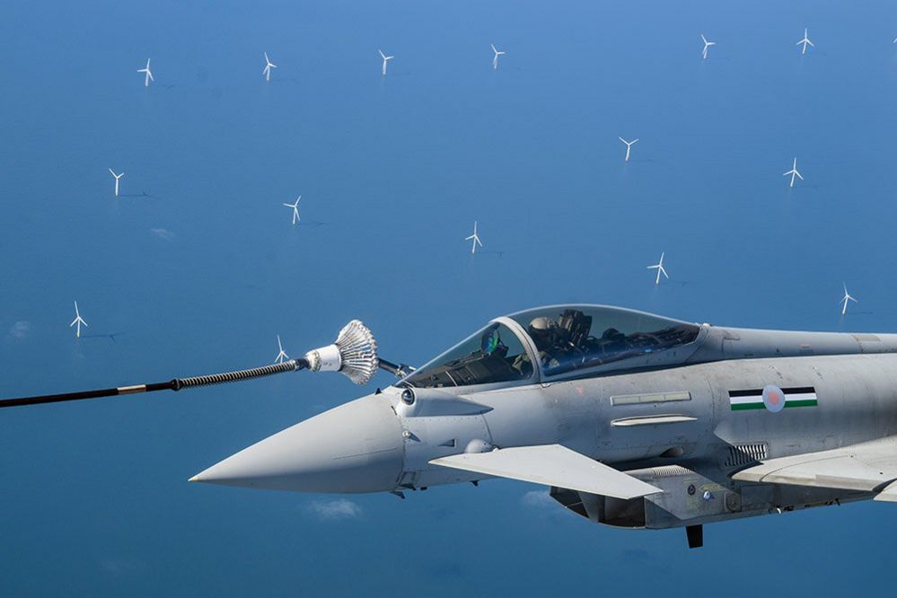 Wind turbines are seen in the distance as an RAF Typhoon fighter jet is refuelled in-flight over the North Sea