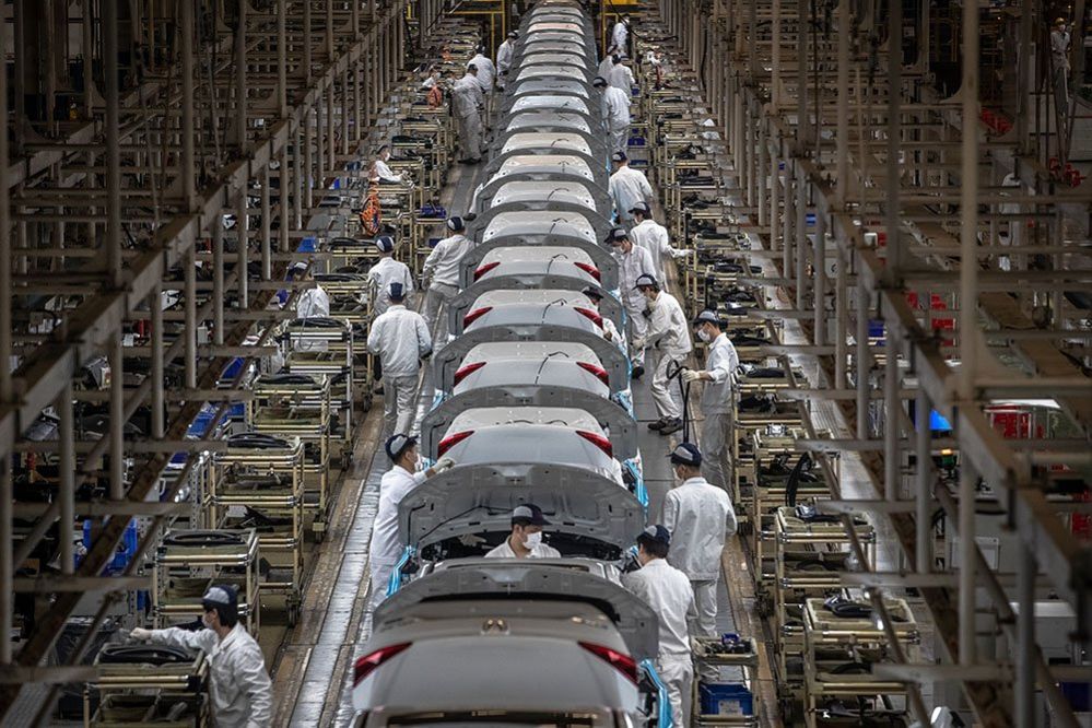 People wearing protective face masks work on an assembly line at the Dongfeng Honda plant in Wuhan