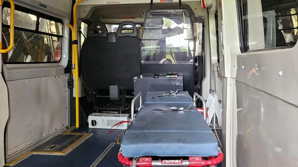 Back of an ambulance showing a stretcher covered in blue mats