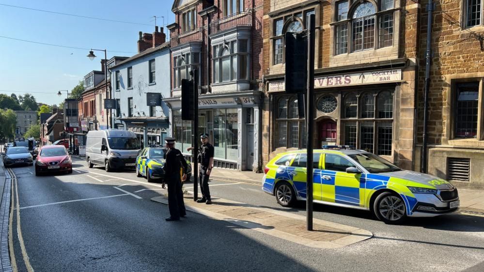 Road junction with two police cars parked by traffic lights and two police officers looking on