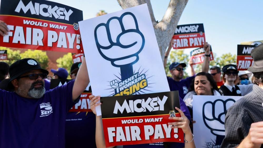 Workers hold up a Mickey Mouse sign on Disneyland protest