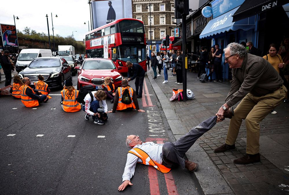 A member of the public drags an activist who is blocking the road during a Just Stop Oil protest