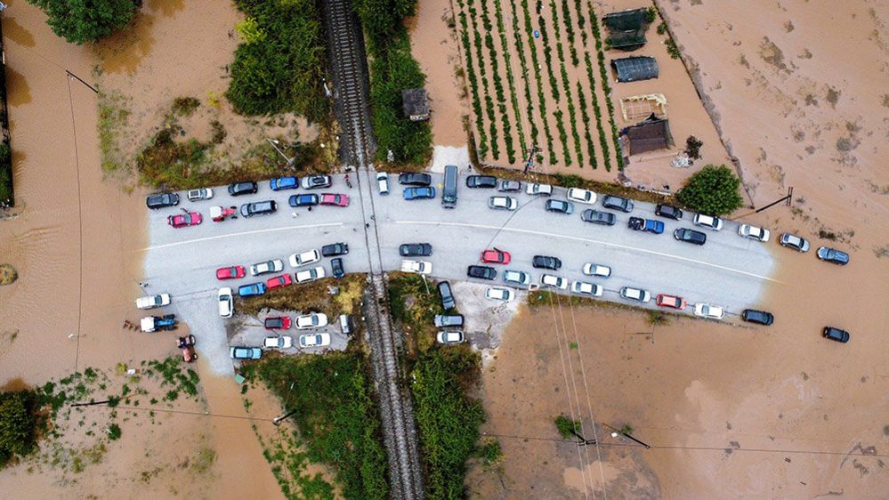 An aerial view of cars stuck on a bridge surrounded by flood water