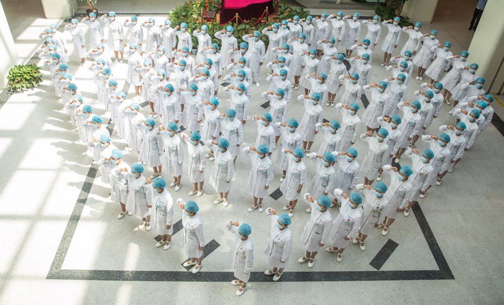 A crowd of nurses stand in the shape of a heart as they recite an oath