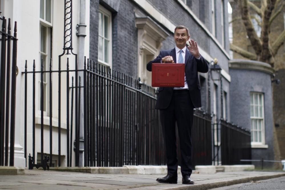 British Chancellor of Exchequer Jeremy Hunt waves at his family as he poses with the Budget box