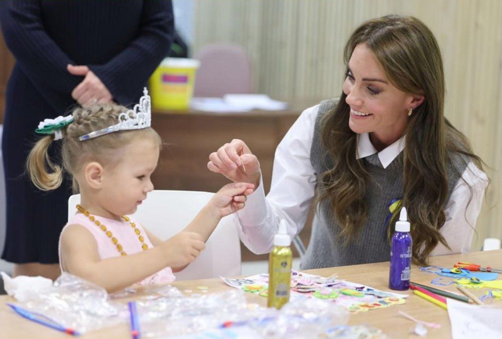 The Princess of Wales helps a young girl at an arts and crafts session