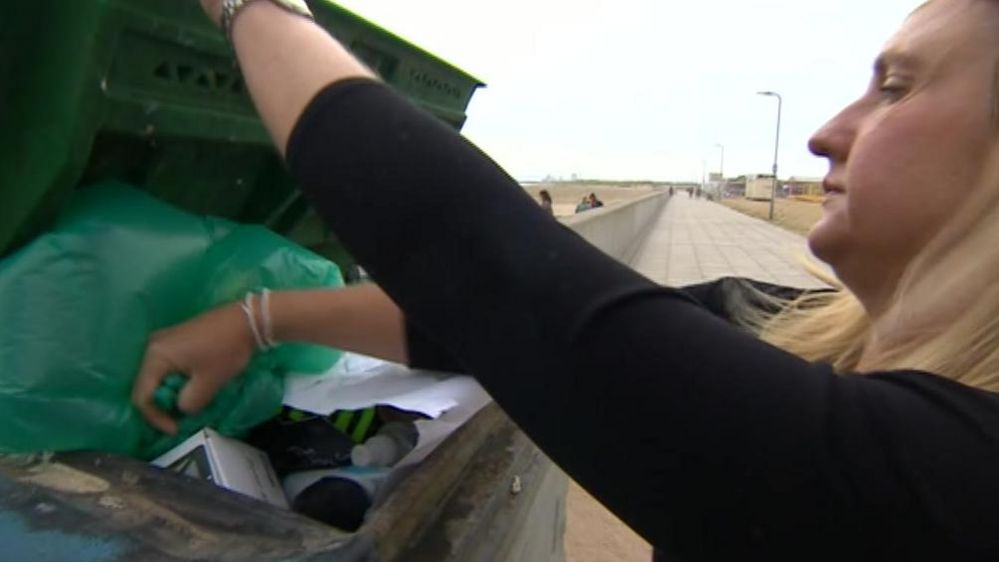 Volunteer putting rubbish inside large bin