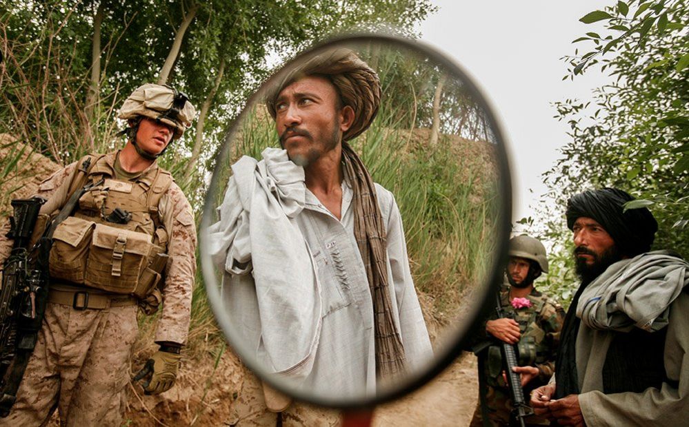 An Afghani citizen is seen in the mirror of his motorcycle after being stopped and searched by US Marines while patrolling in the Karez-e Sayyidi area near Marjah district in Helmand, Afghanistan, 2010