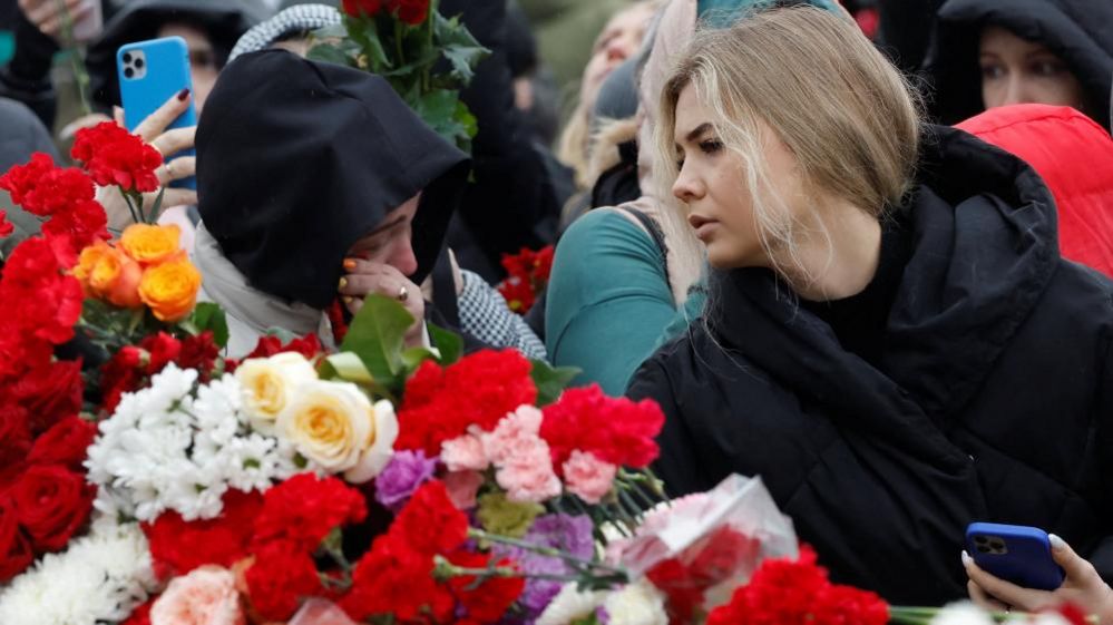 People lay flowers at a makeshift memorial to the victims of a shooting attack set up outside the Crocus City Hall concert venue in the Moscow Region, Russia, March 24, 2024