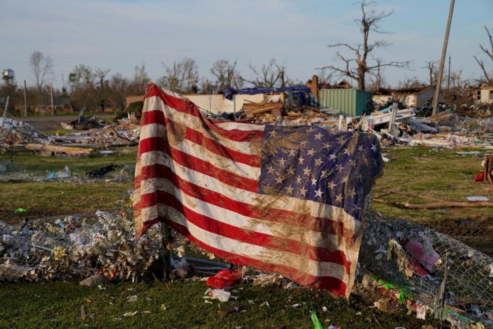 A muddied American flag is seen draped over wreckage in Rolling Fork, Mississippi
