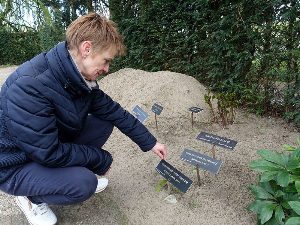 Detective Carina van Leeuwen crouches in a cemetery to examine the plaque of an unidentified woman