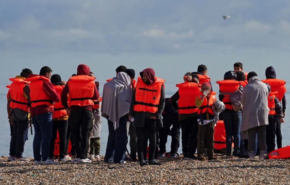A group of people thought to be migrants on the beach in Dungeness, Kent, after being rescued in the Channel by the RNLI following following a small boat incident