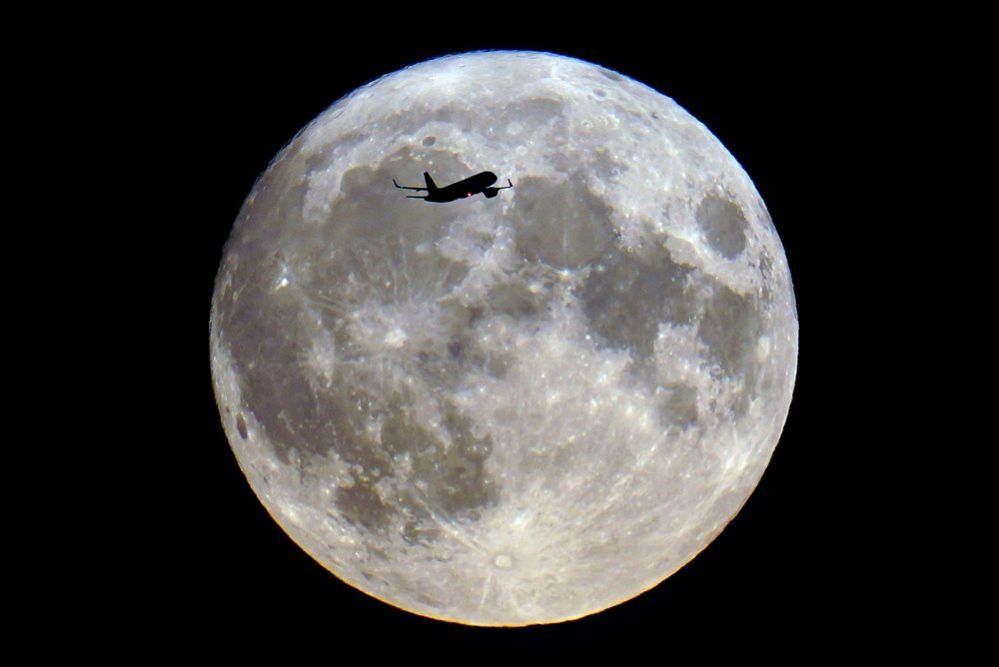 A plane passes the super blue moon in London