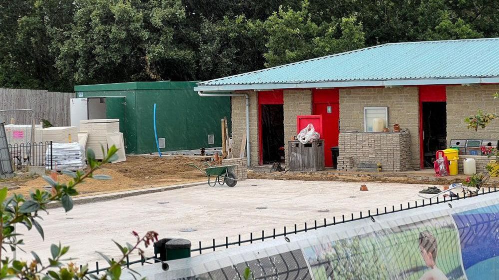 A building site with concrete foundations and small building almost completed