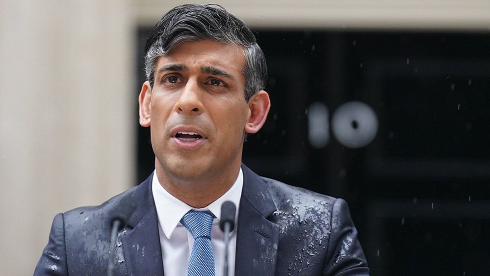 Rishi Sunak headshot in suit and tie while with the number 10 out of focus in the background, outside Downing Street on 22 May