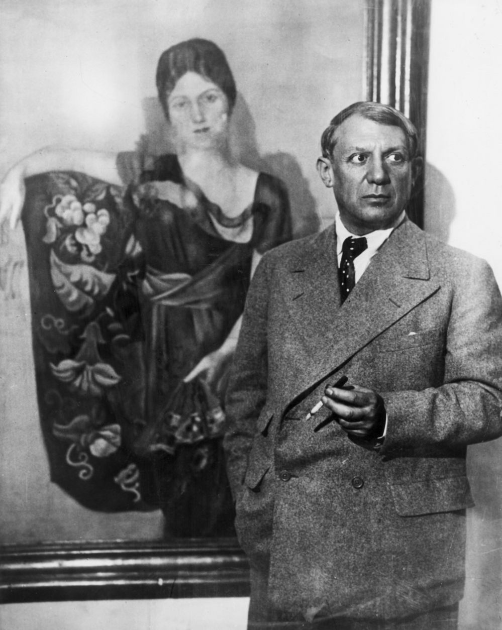 Пикассо стоит перед созданным им портретом своей жены Ольги Хохловой