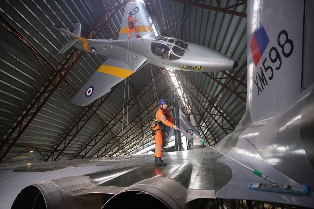 Two men clean military aircraft at Royal Air Force Museum Midlands, in Cosford