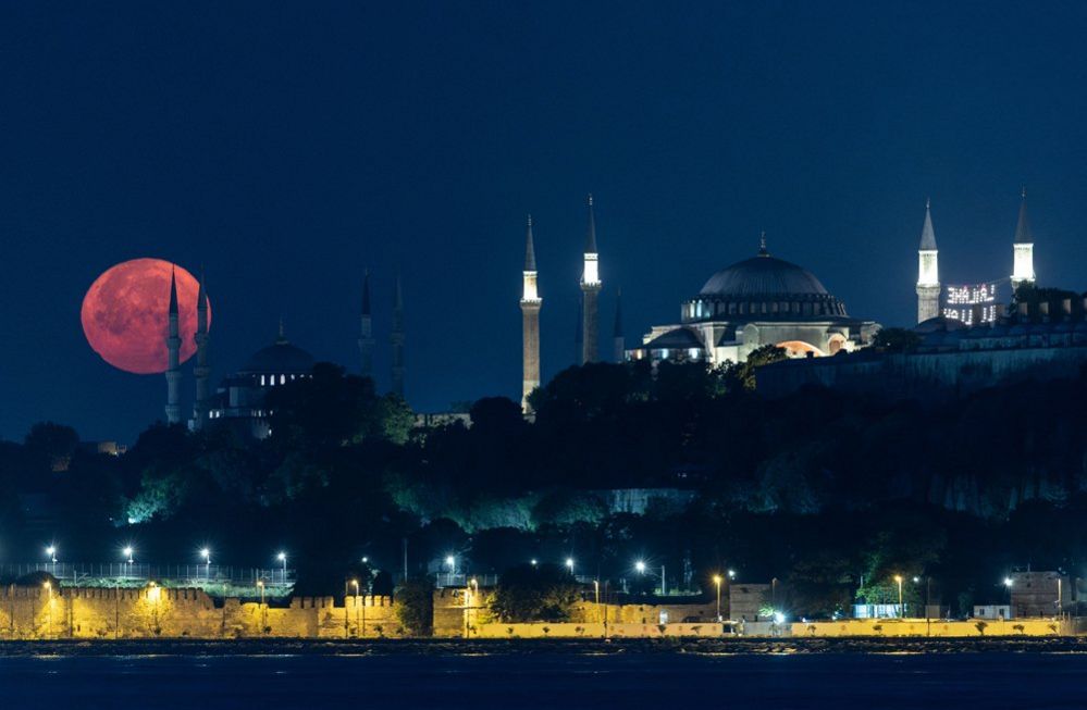 Una luna llena se pone detrás de la Mezquita Azul y la Gran Mezquita de Santa Sofía, en Estambul, Turquía, 03 de julio 2023