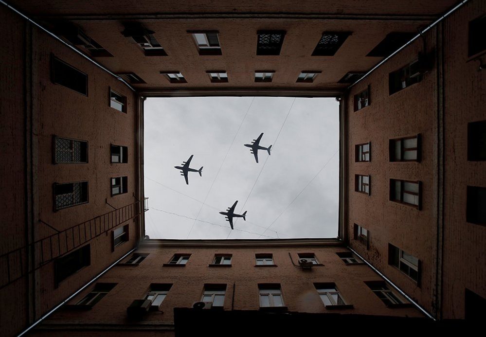 Three military aircraft fly over a building