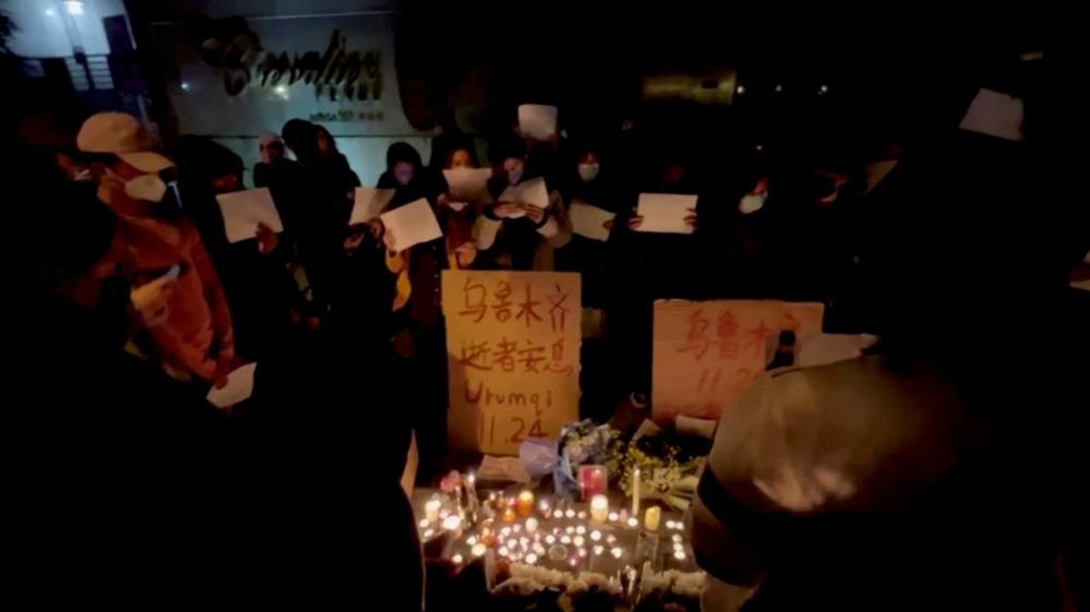 People hold a candlelit vigil for the victims of the Urumqi fire in Shanghai