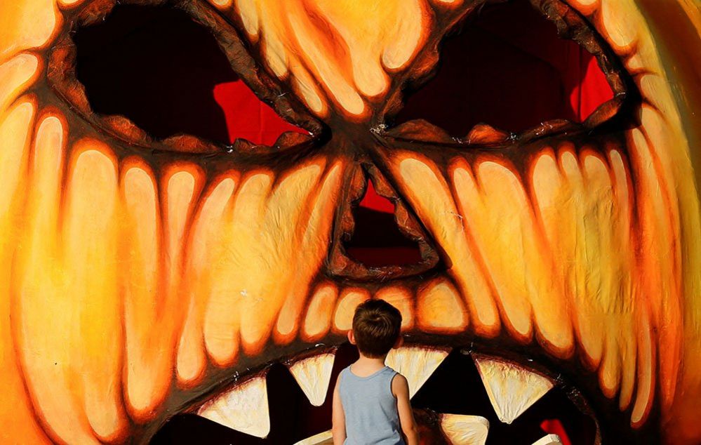 A child looks at a giant Halloween pumpkin