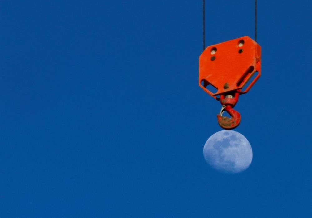 The Moon rises behind a crane