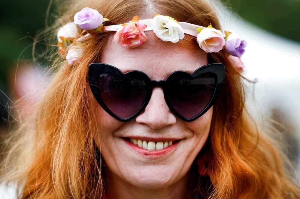 Virginia, 47, from Paris, poses successful  heart-shaped sunglasses and a roseate  garland astatine  the festival