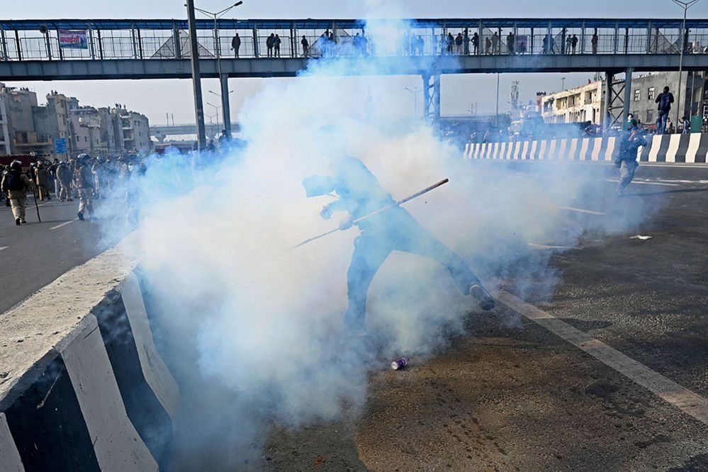 A farmer throws back a tear gas shell