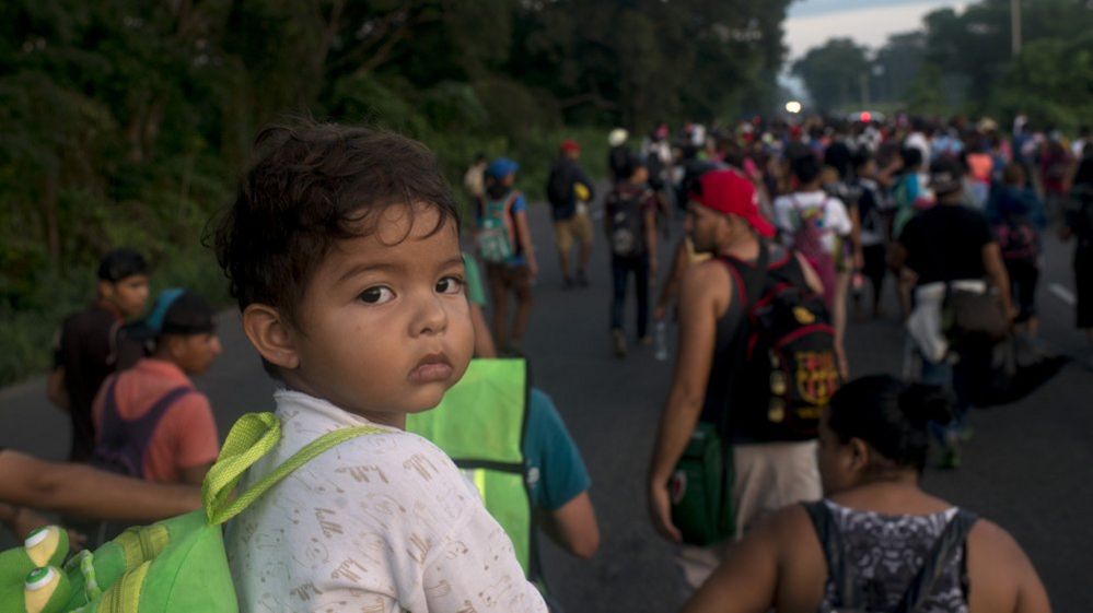 A father carries a child on his shoulders as the migrant caravan advances towards the Mexican city of Tapachula