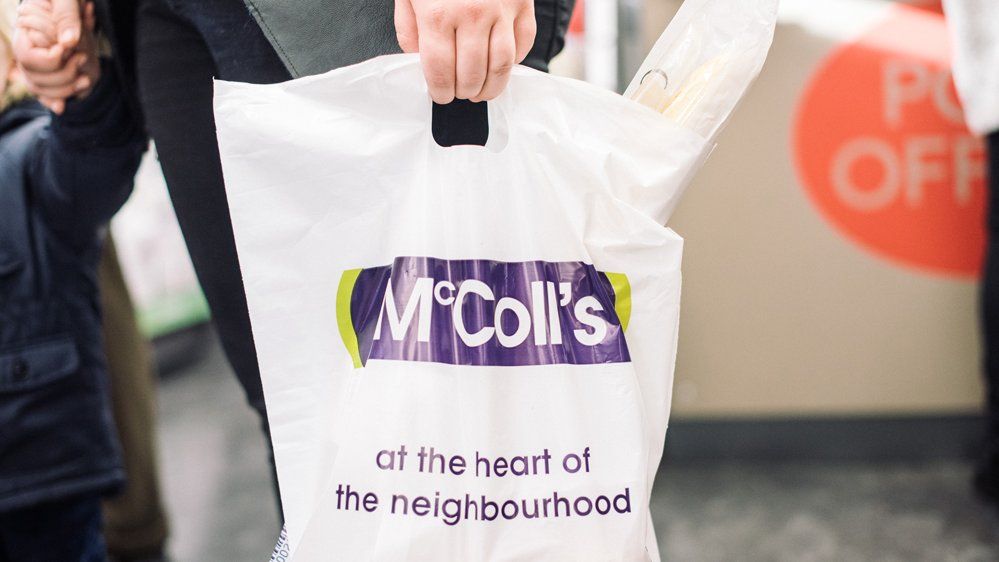 Person carrying a McColl's branded bag