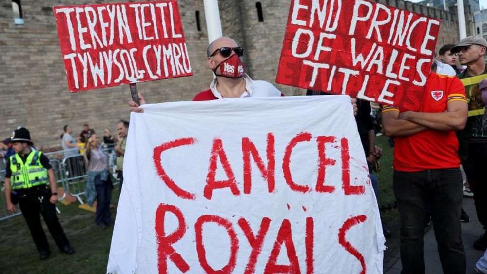 A man holds signs and a banner during a protest outside Cardiff Castle on 16 September, the King's first visit to Wales since the death of the Queen
