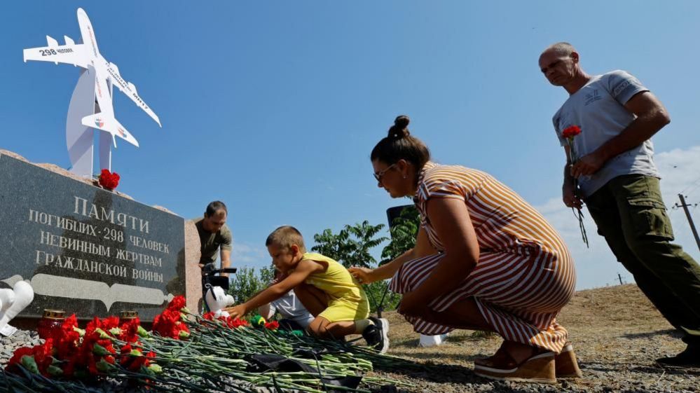 People place flowers and toys at a memorial to victims of the MH17 plane crash during a ceremony marking the 10th anniversary of the accident, near the village of Hrabove (Grabovo)