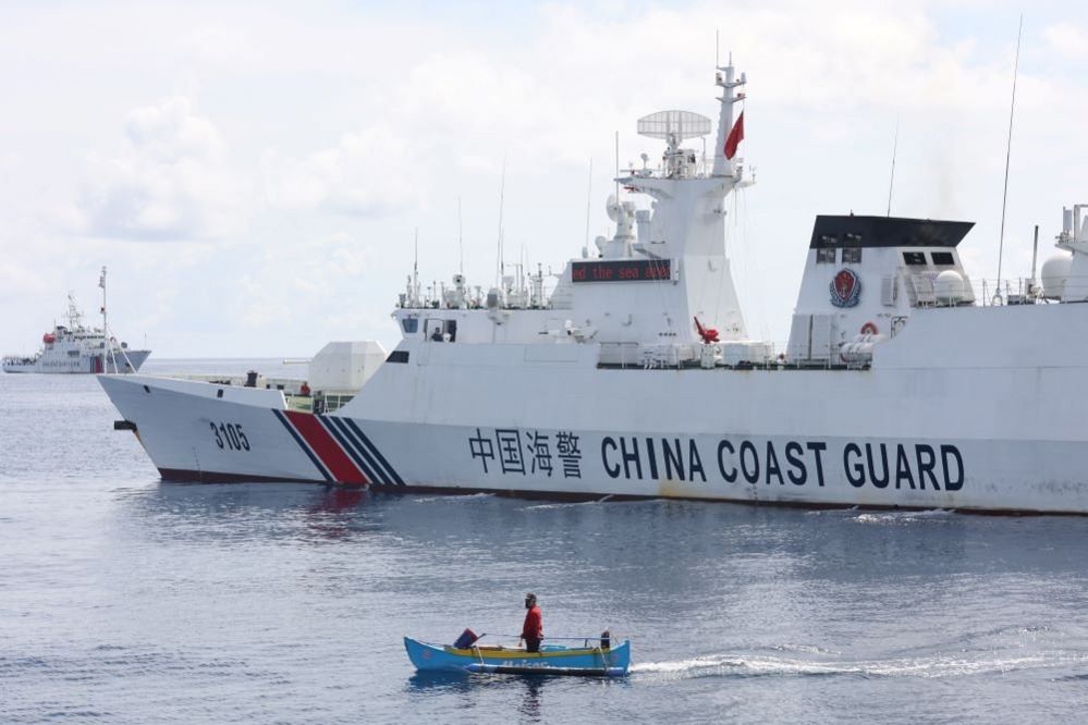 Arnel Satam stands in his wooden boat beside the China Coast Guard, 22 September 2023.