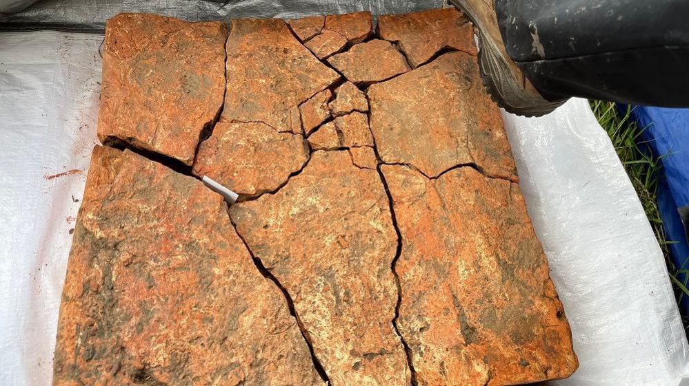 A large terracotta coloured slab with cracks