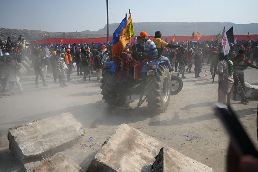 Farmers on a tractor prepare to remove concrete barricades installed by police