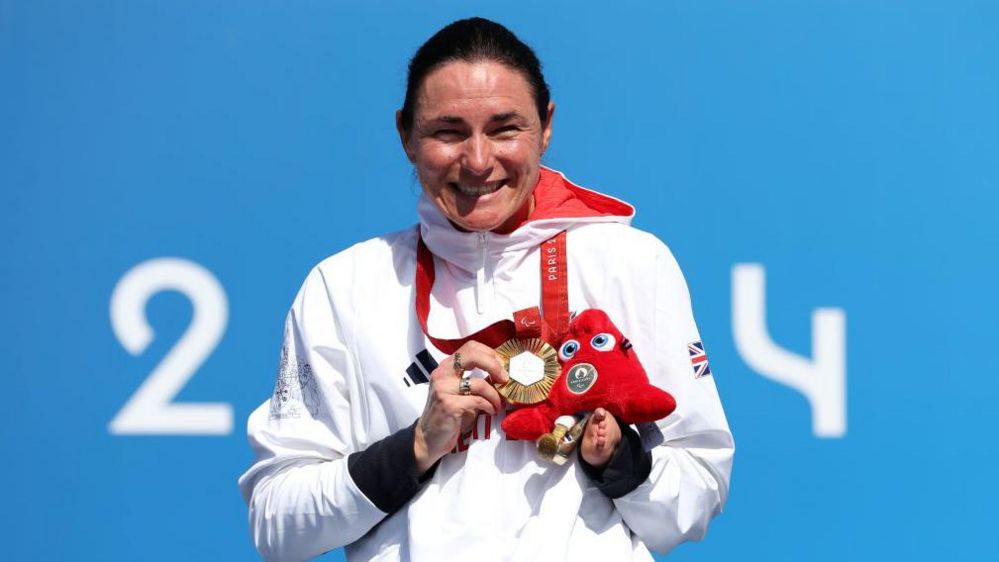 Sarah Storey smiles while holding her gold medal