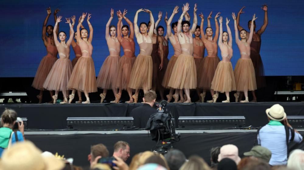 Group of ballet dancers on stage, their arms above their heads